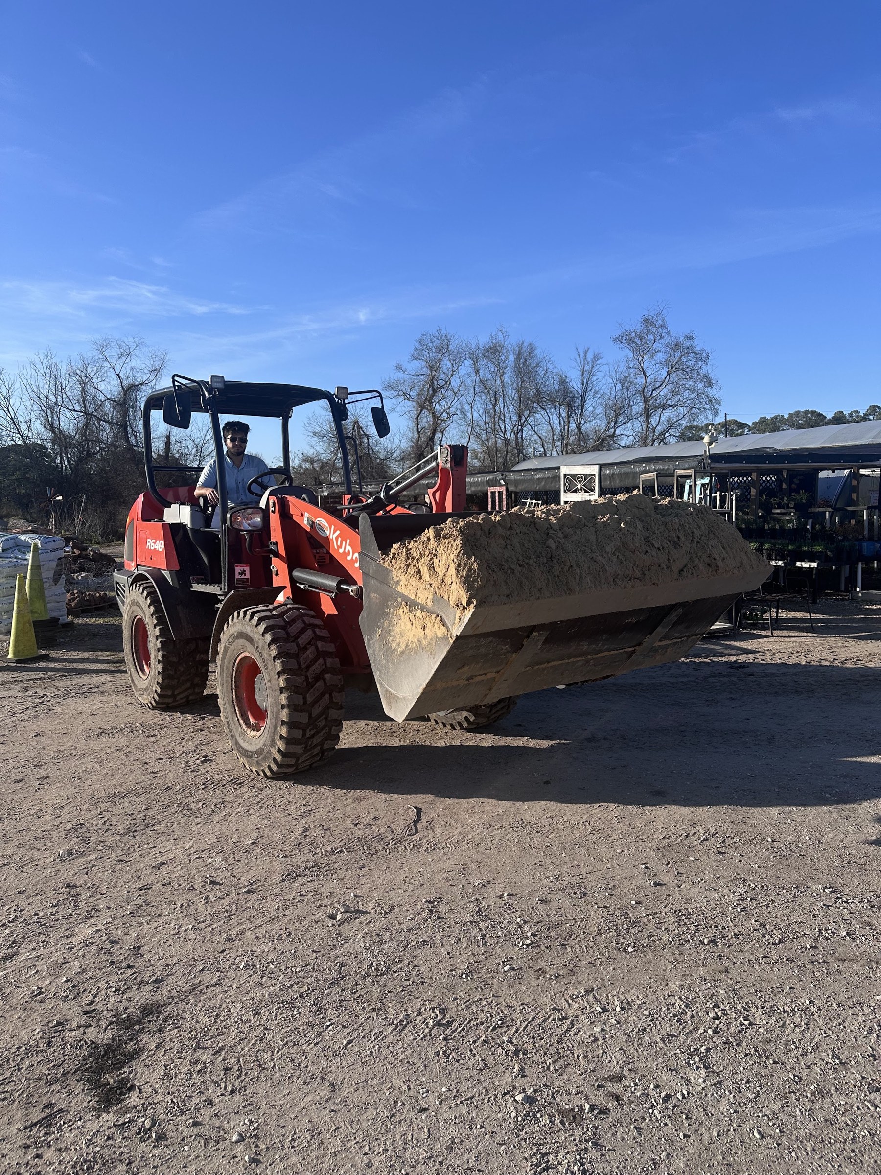 Compact loader carrying bulk material across the crushed limestone yard